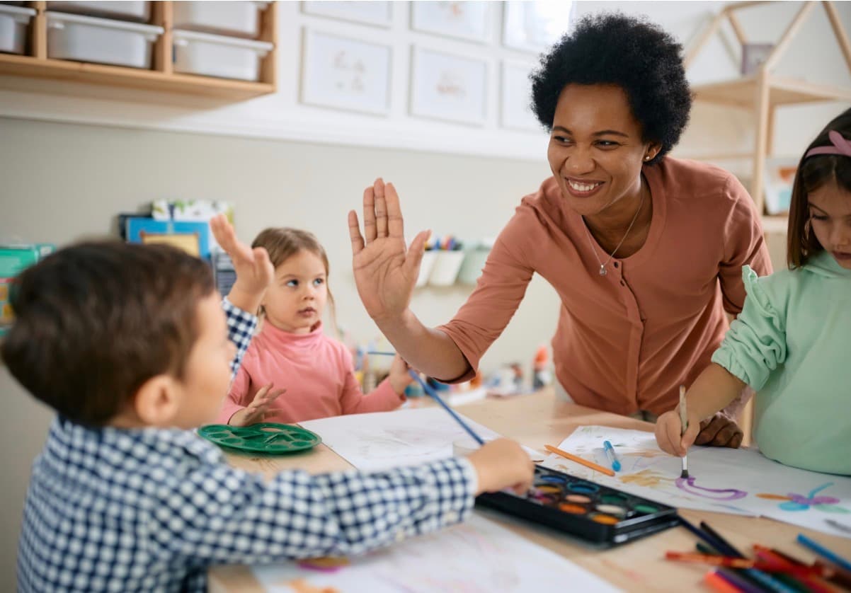 Une éducatrice donne un high-five à un enfant lors d'une activité de peinture